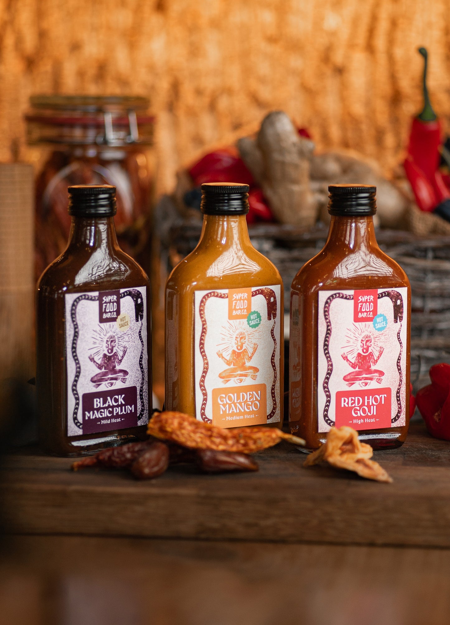 Opened gift box with three fermented hot sauces — Red Hot Goji, Golden Mango, and Black Magic Plum — in glass bottles from Superfood Bar Co.