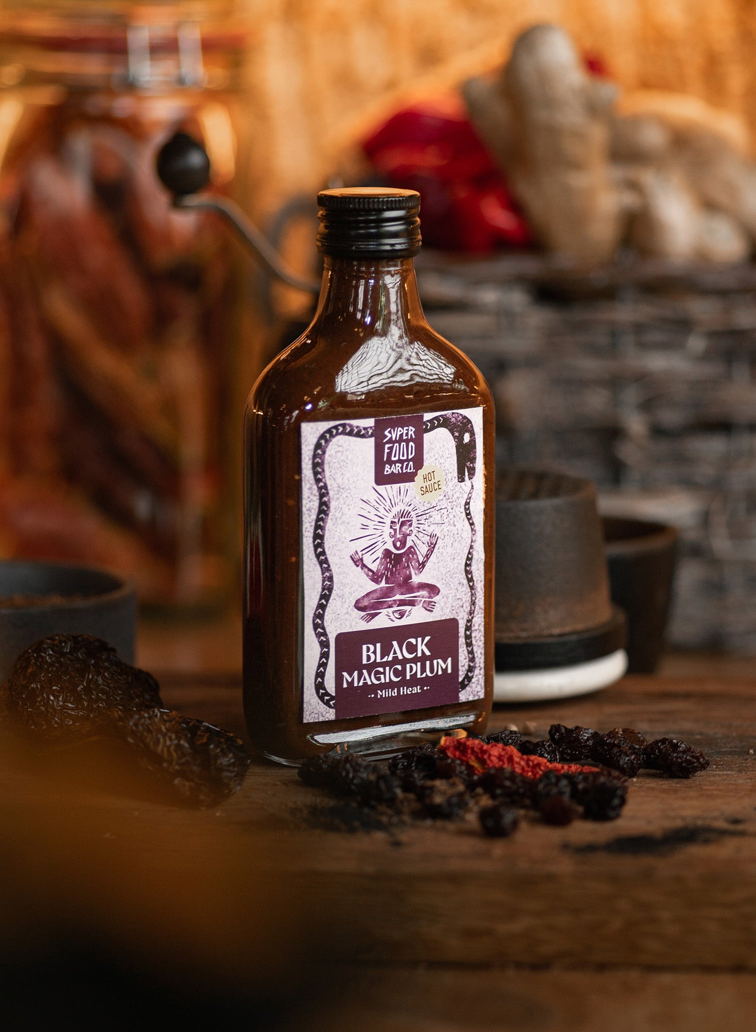 Black Magic Plum hot sauce bottle with fresh ingredients and styled background