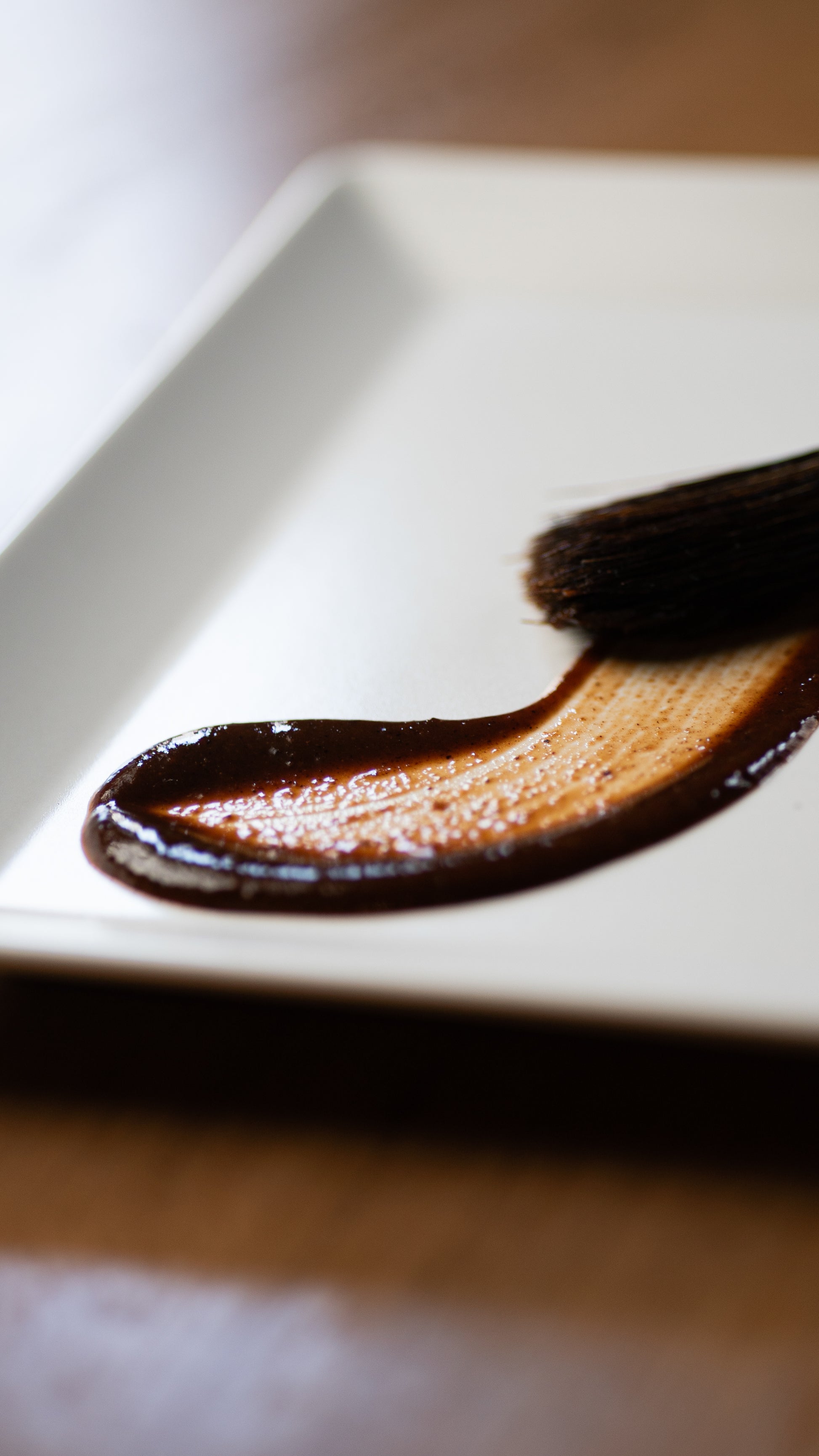 Black Magic Plum hot sauce spread on a white plate for texture