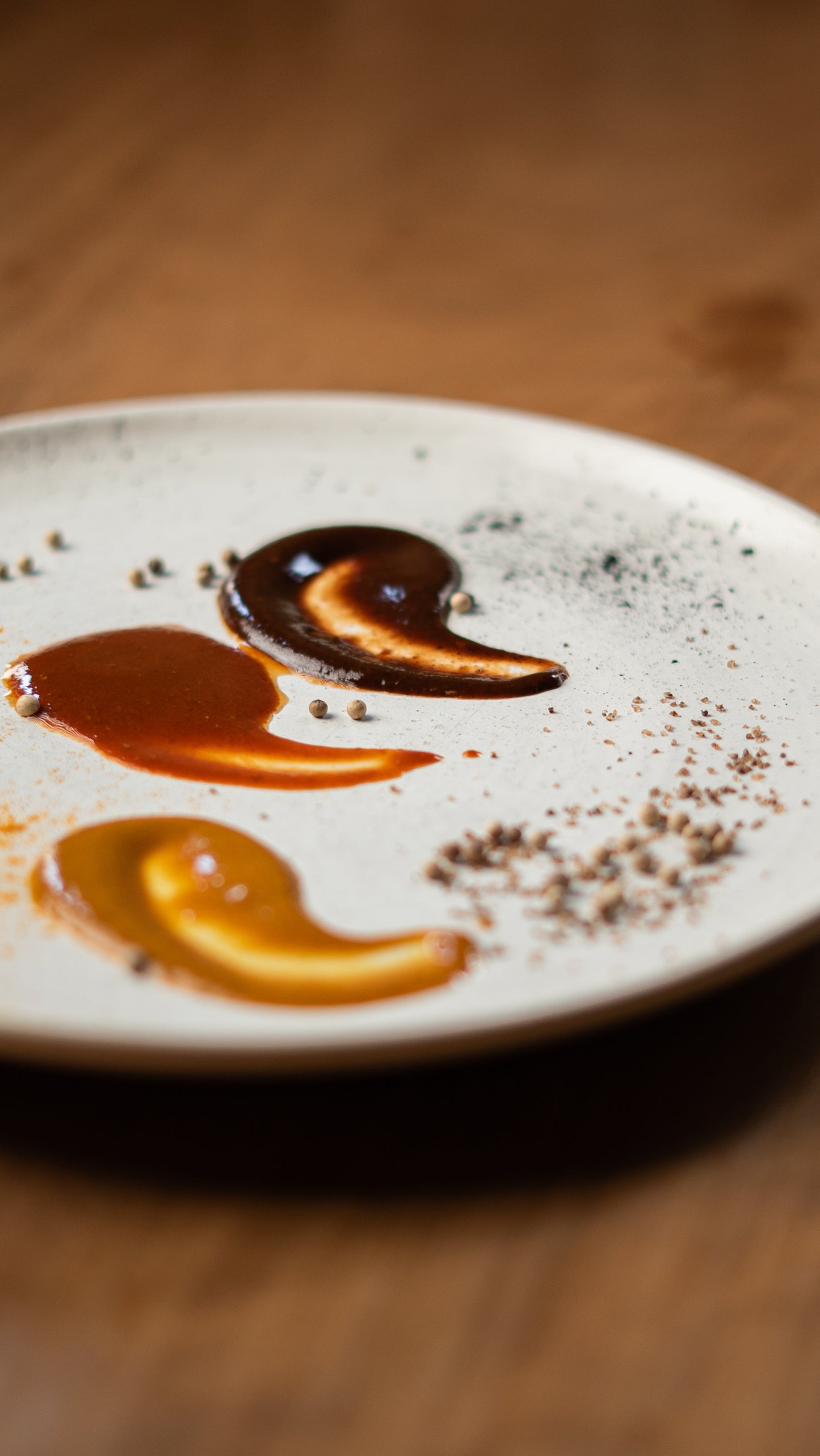 Three fermented hot sauces — Red Hot Goji, Golden Mango, and Black Magic Plum — served on a plate with natural spices, crafted by chef Joseph Stone