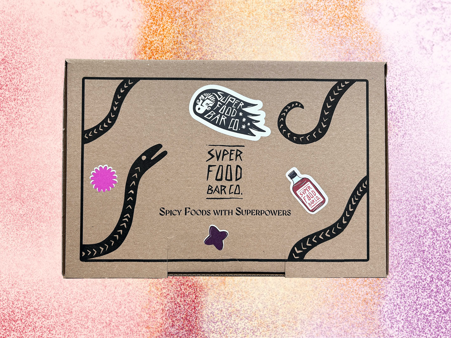 Closed Superfood Bar Co. gift box with graphic label design and product stickers, shown on a colorful background