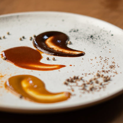Three fermented hot sauces — Red Hot Goji, Golden Mango, and Black Magic Plum — served on a plate with natural spices, crafted by chef Joseph Stone