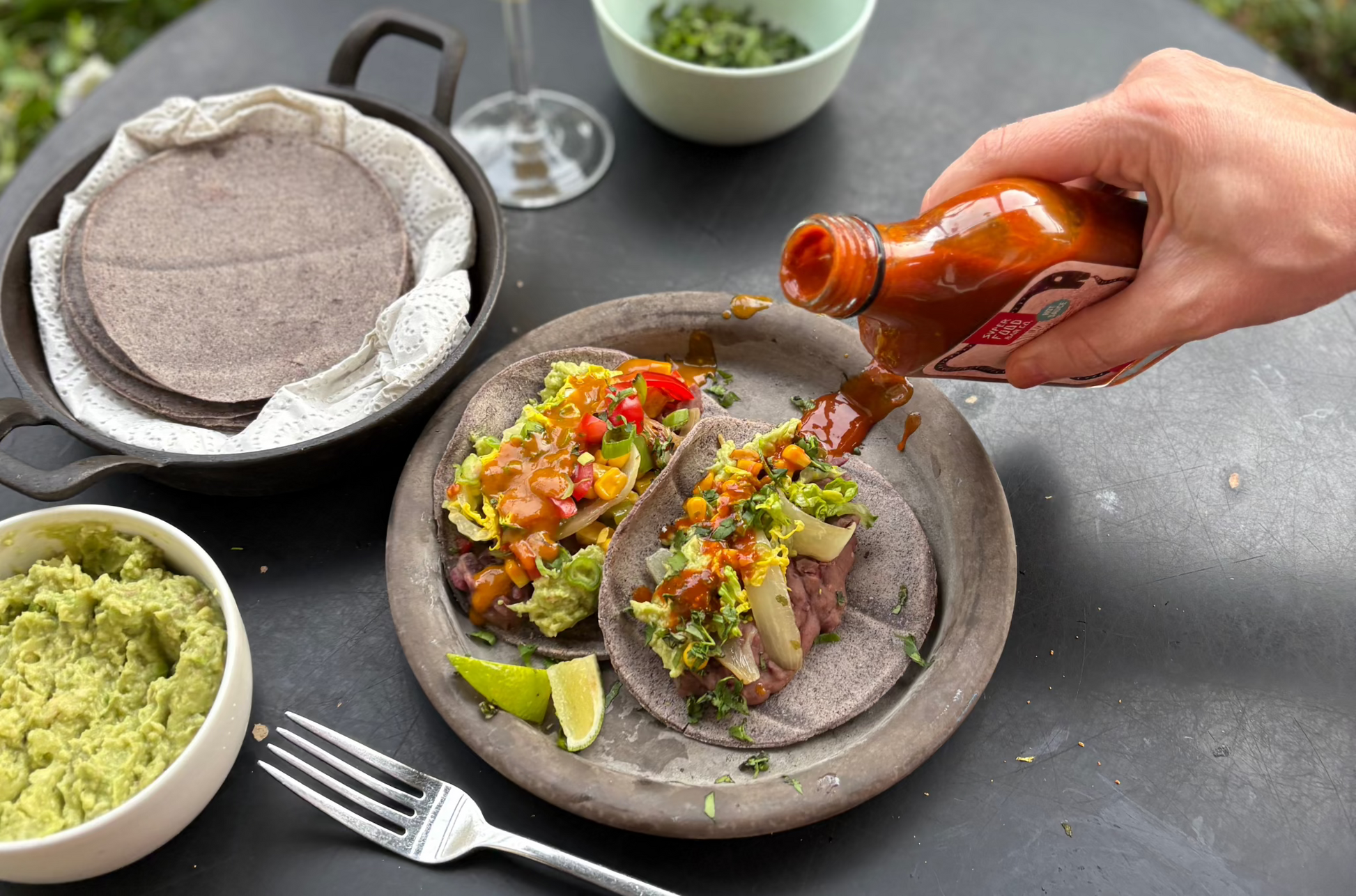 Pouring Red Hot Goji hot sauce over a taco