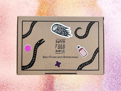Closed Superfood Bar Co. gift box with graphic label design and product stickers, shown on a colorful  background

